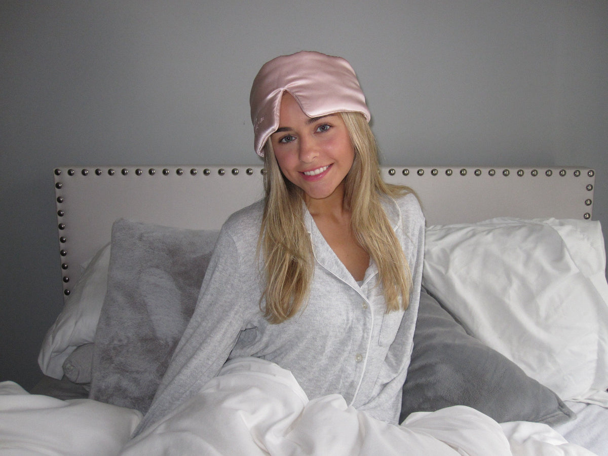 Woman resting in bed wearing an Owl Sleep Co silk sleep mask